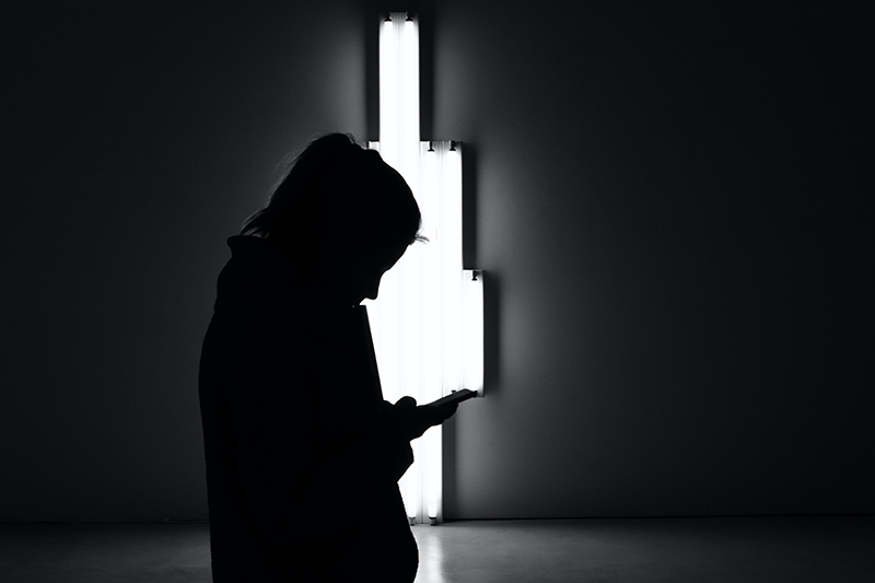 woman standing holding cell phone black and white