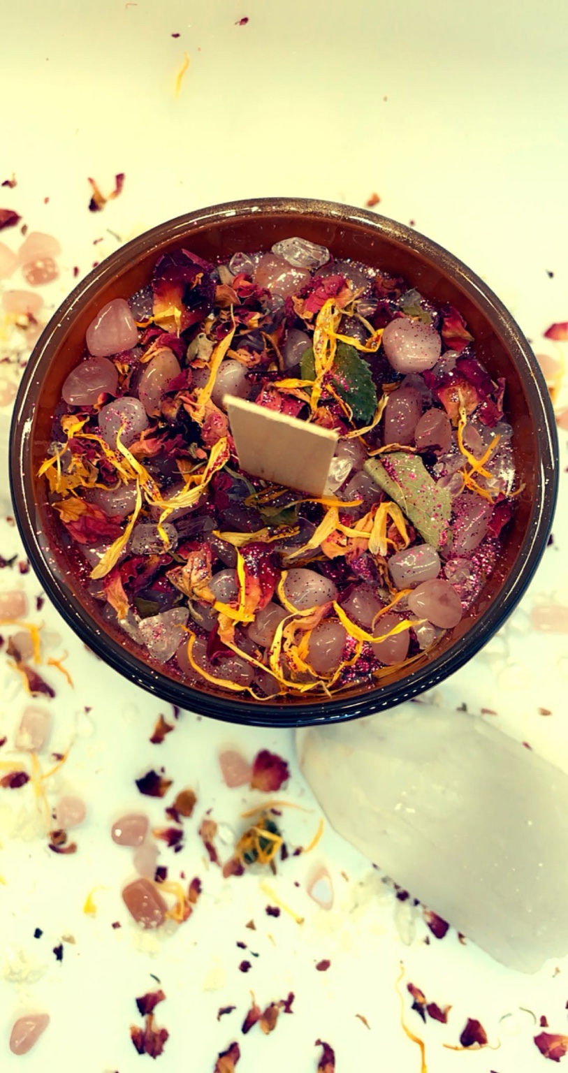 Close-up top view of a candle filled with crystals and dried flowers.